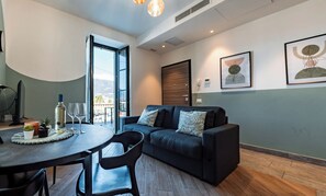 Una sala de estar moderna con un sofá, una mesa de comedor con sillas, un ventanal grande y obras de arte en las paredes.