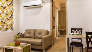 A living room with a beige sofa, a small table with a plant, and a dining area with a wooden table and chairs. - SILVER OAK (Gurugram)