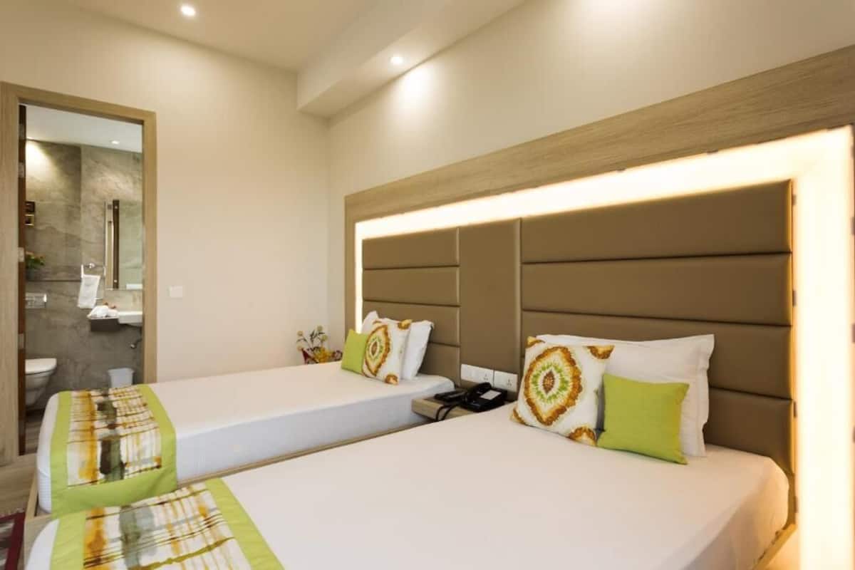A hotel room with two beds, a mirror, and a bathroom visible through an open door.