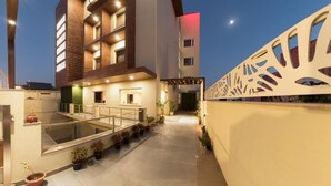 A modern building with a pool area, potted plants, and a decorative wall. - SILVER OAK (Gurugram)