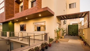 A modern building with a covered outdoor area, potted plants, and a staircase. - SILVER OAK (Gurugram)