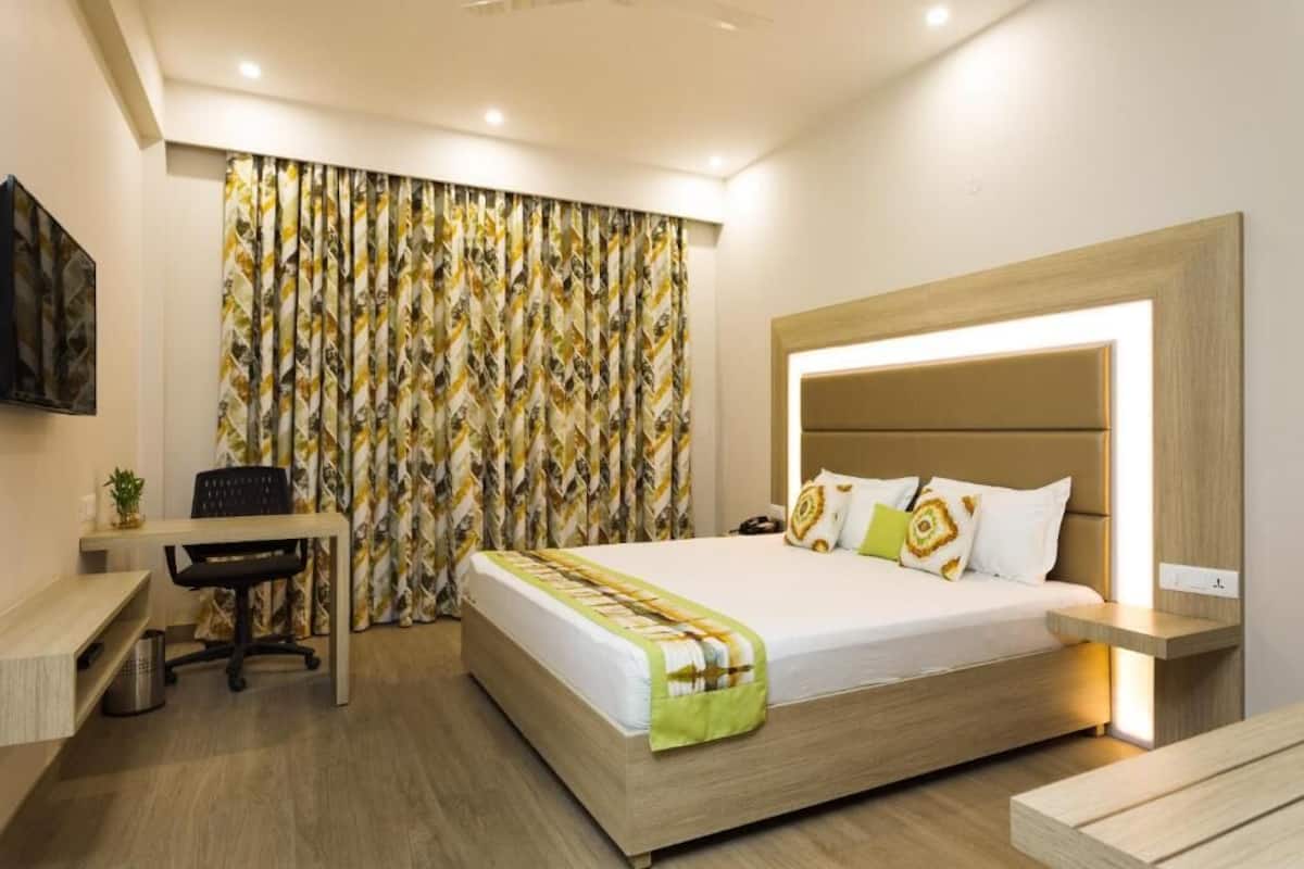 A modern hotel room with a wooden bed, a desk, and a chair.