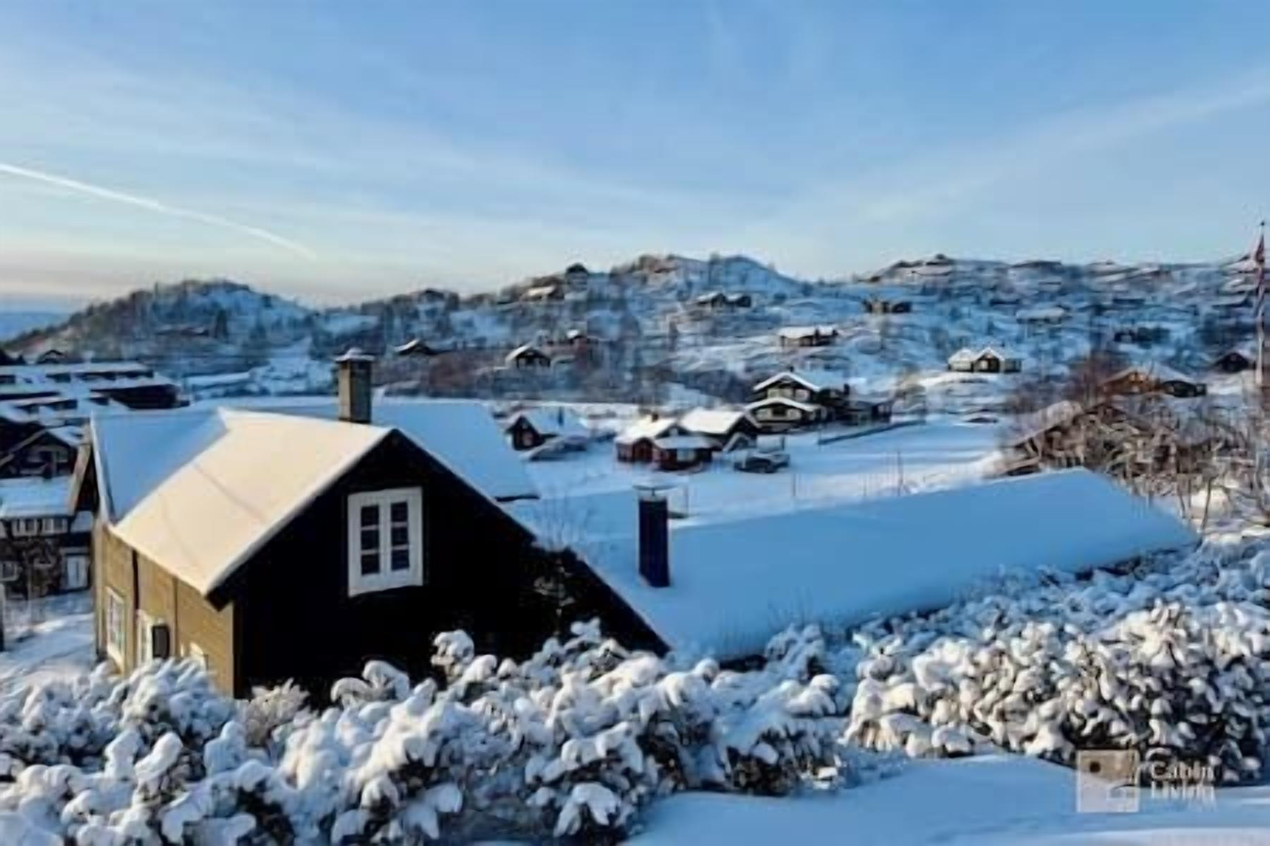 Ein schneebedecktes Dorf mit Häusern und einem markanten, schwarzen Gebäude mit einem weißen Fenster.