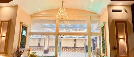 A grand entrance with a chandelier, a reception desk, and a view into a spacious hall with seating.