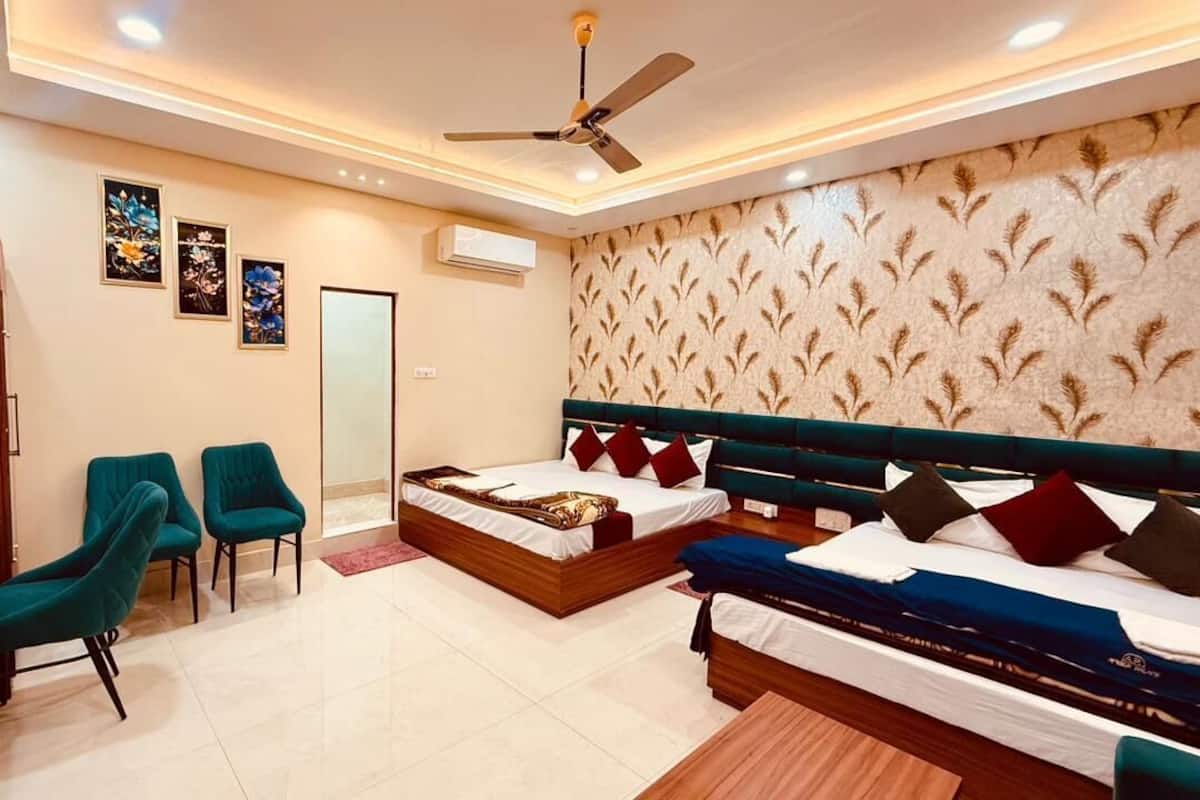 A hotel room with a bed, two chairs, a desk, and a ceiling fan.