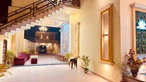 A spacious lobby with a staircase, seating area, and a reception desk. - Amber Palace (Faizabad)