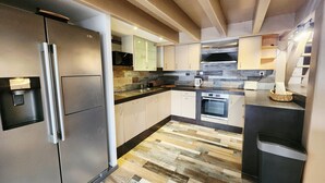A modern kitchen with a stainless steel refrigerator, a built-in oven, and a microwave. - Pool and spa villa by the lake (Sanguinet)
