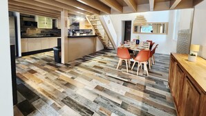 A modern kitchen with wooden cabinets, a dining area with a wooden table and chairs, and a staircase leading to another level. - Pool and spa villa by the lake (Sanguinet)