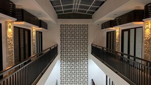 Un interno moderno con una parete centrale forata, ringhiere in metallo e decorazioni parietali a motivi.