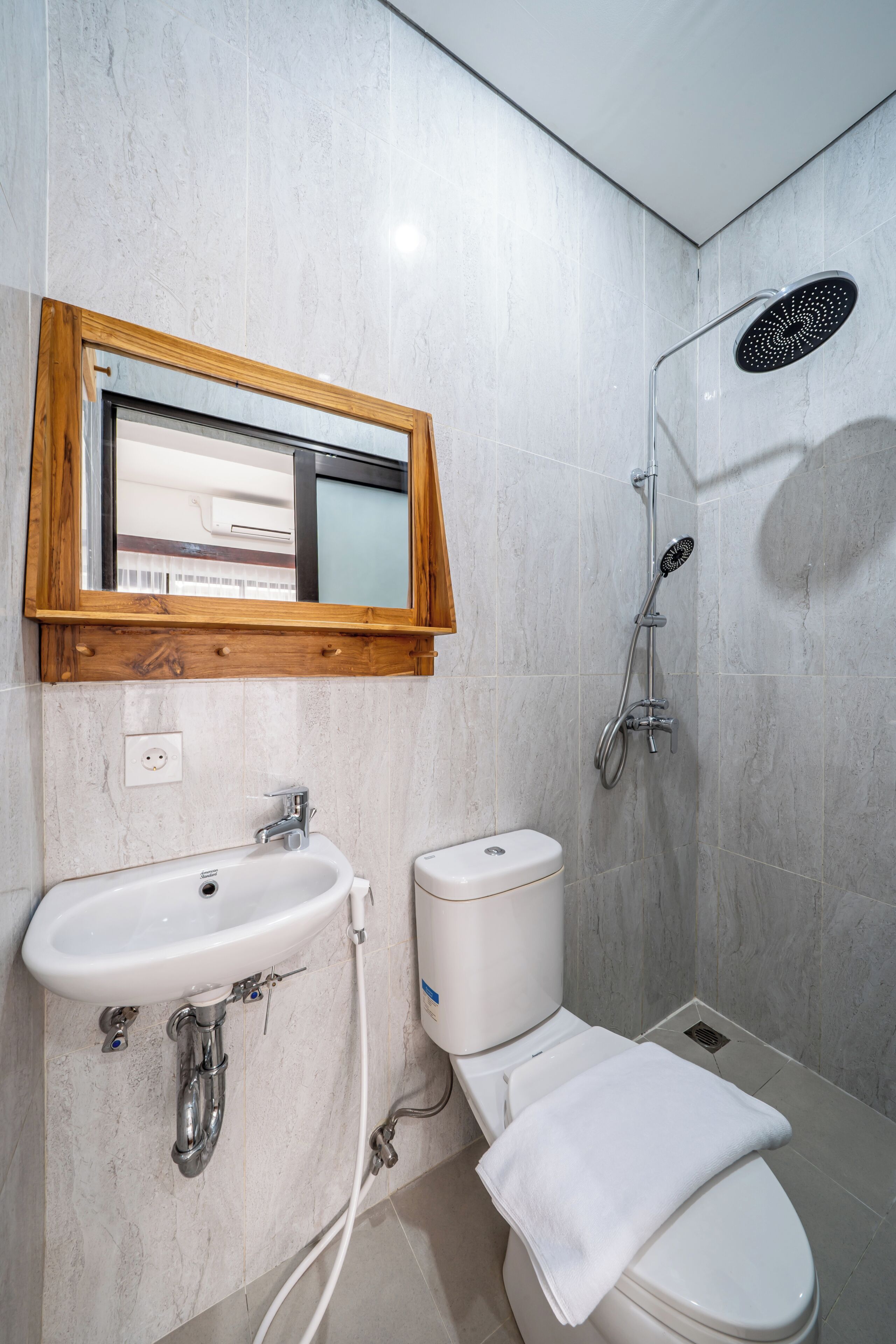 A bathroom with a sink, toilet, mirror, and shower.
