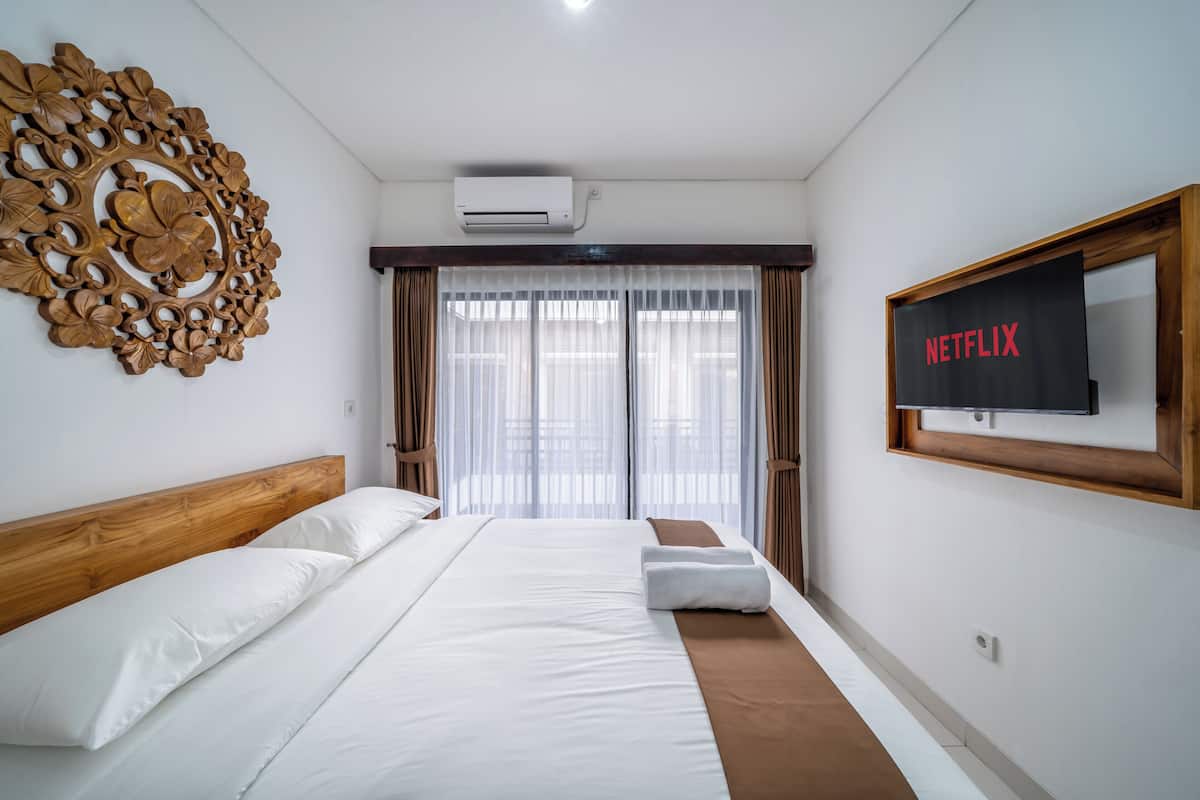 A hotel room with a bed, a wall-mounted TV, and a large decorative wall piece.