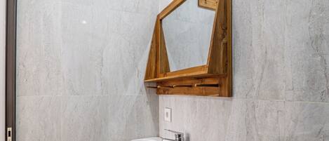 Un baño con un lavamanos blanco, un espejo con marco de madera y un inodoro.