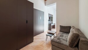 A modern living room with a sofa, a small table, and a wardrobe. - Large 6-Bed Stay near the Colosseum (Rome)
