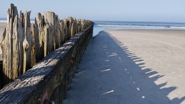 Ein Strand mit einer hölzernen Steg, der sich ins Meer erstreckt.
