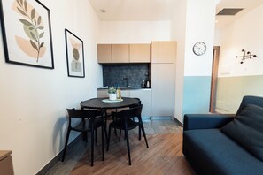 A compact living space with a dining area, kitchenette, and a dark-colored sofa. - Lavanda - Modern apartment in a 19th-century villa. 5 minutes from the station (Bellano)