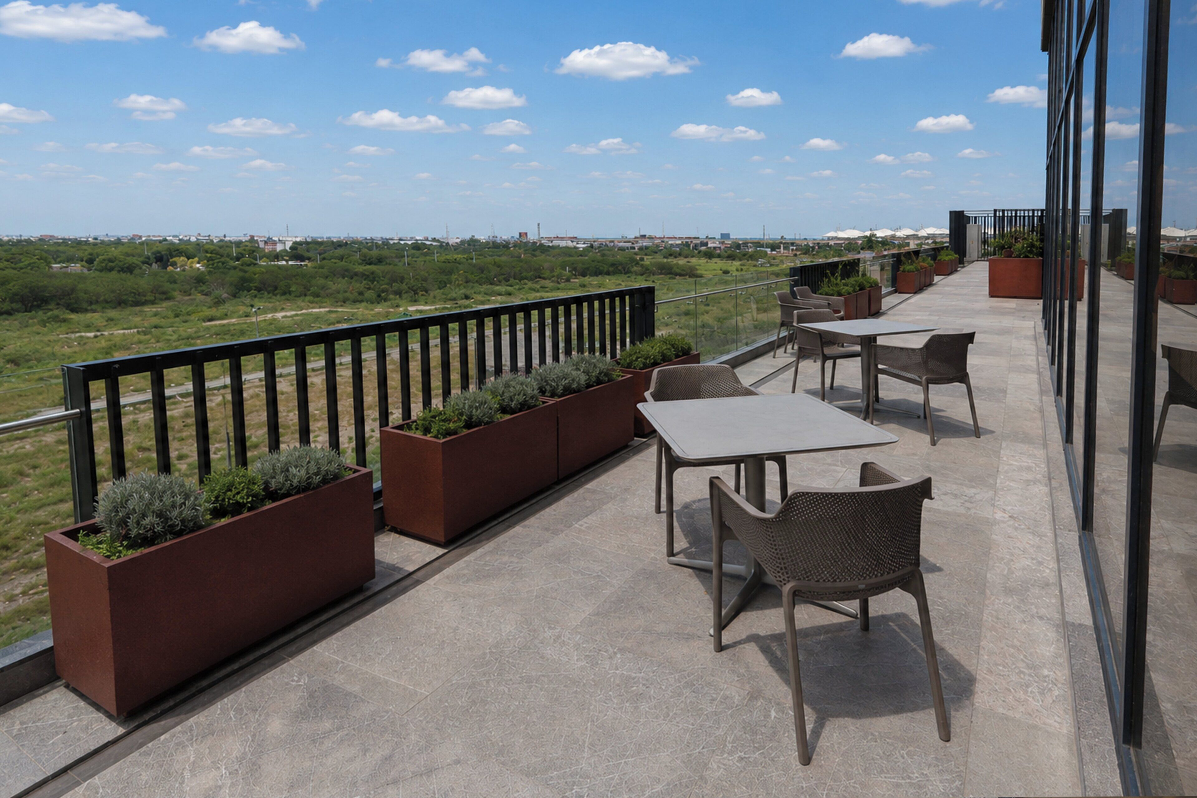 A balcony with outdoor seating, a railing, and potted plants.