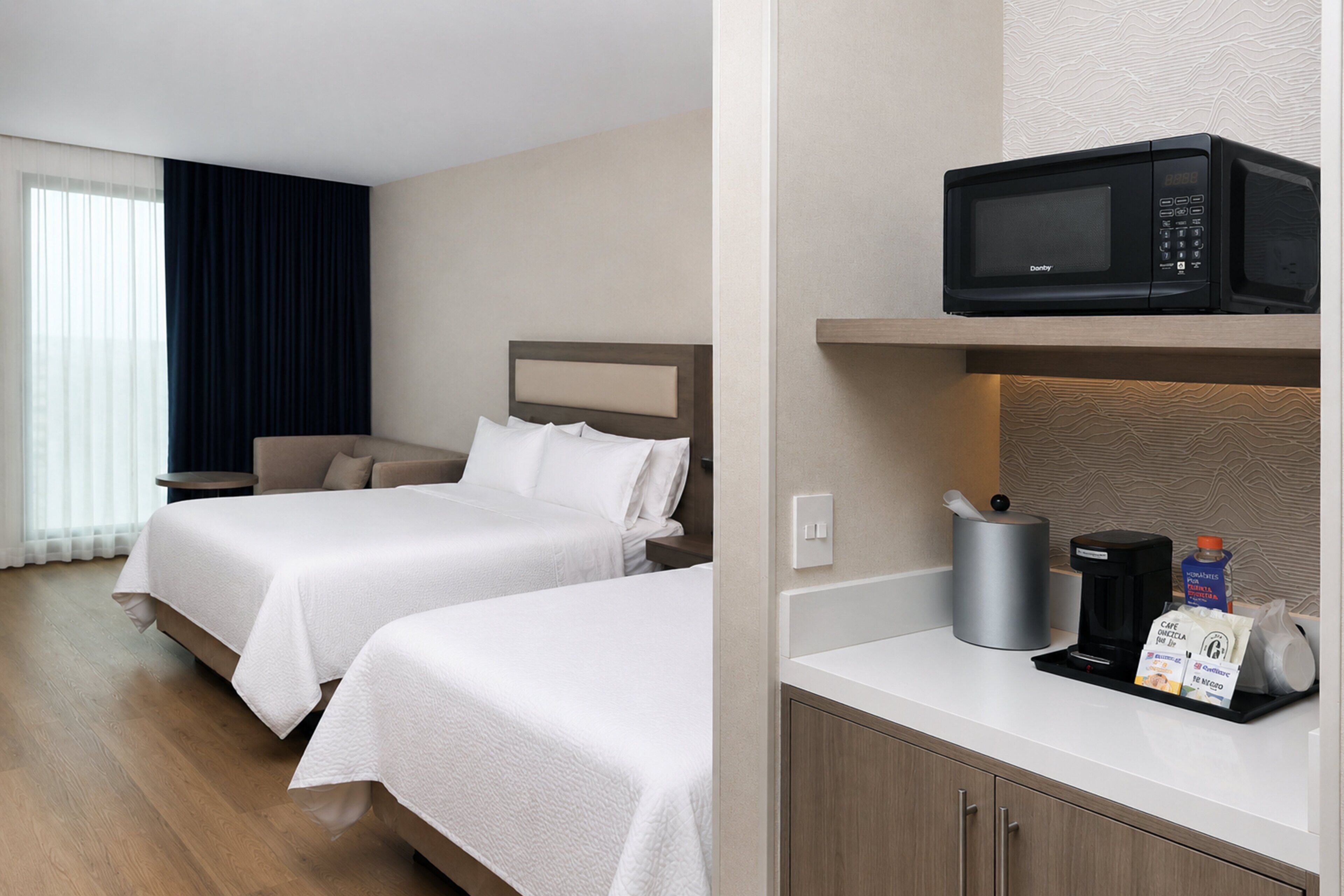 Une chambre d’hôtel avec deux lits, une machine à café, un four à micro-ondes et un petit placard.