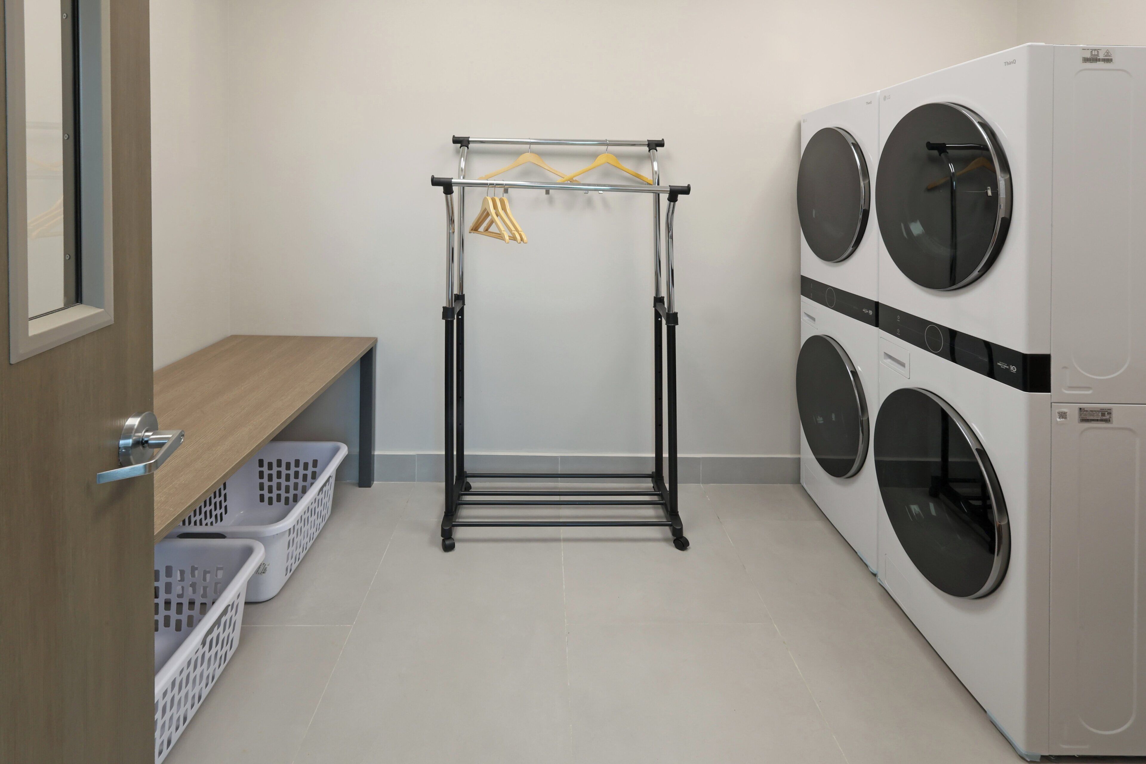 Un espace buanderie équipé d’un étendoir, de deux machines à laver et de paniers à linge.