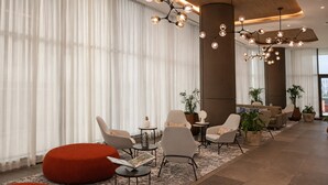Un vestíbulo moderno con zonas de estar, ventanas amplias e iluminación decorativa.