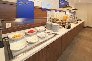 A buffet counter with various food items and a sign indicating breakfast options.