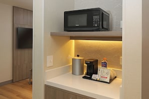 A kitchen area with a microwave, coffee maker, and a coffee pod dispenser. - Holiday Inn Express And Suites Monterrey Sendero (Escobedo)