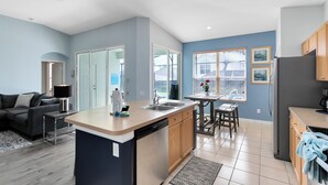 Una cocina moderna con una isla central, armarios de madera y una zona de comedor con mesa y sillas.