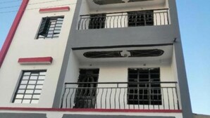 Un edificio de varios pisos con balcones, detalles en rojo y un cielo despejado.