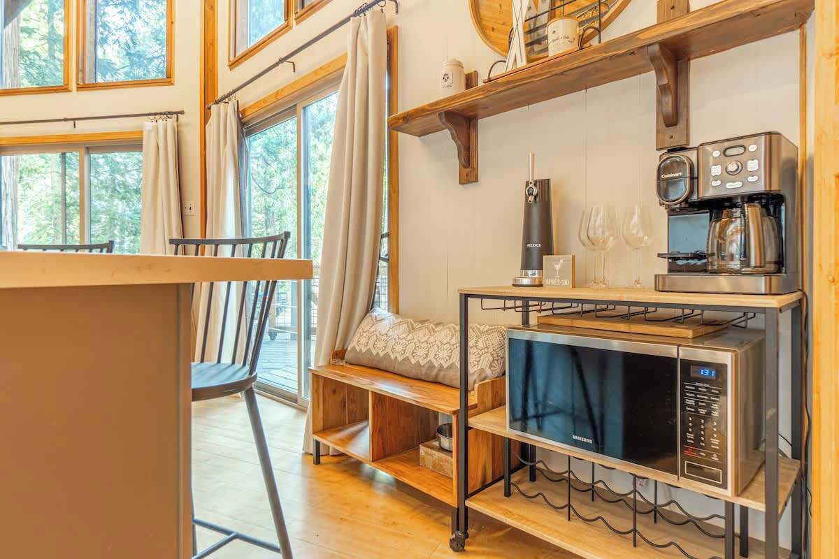 A cozy kitchen with a built-in microwave, coffee maker, and wine glasses on the wall.