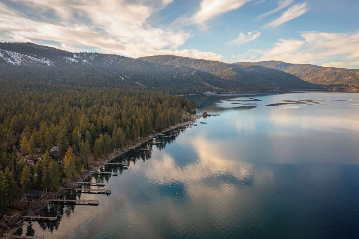 Un lac entouré de montagnes boisées, avec une jetée qui s’avance sur l’eau.