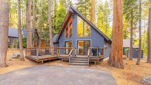 A modern cabin with a large deck, surrounded by tall trees. - West Shore Tahoe Cabin - Loft Movie Nights, Pets (Tahoma)