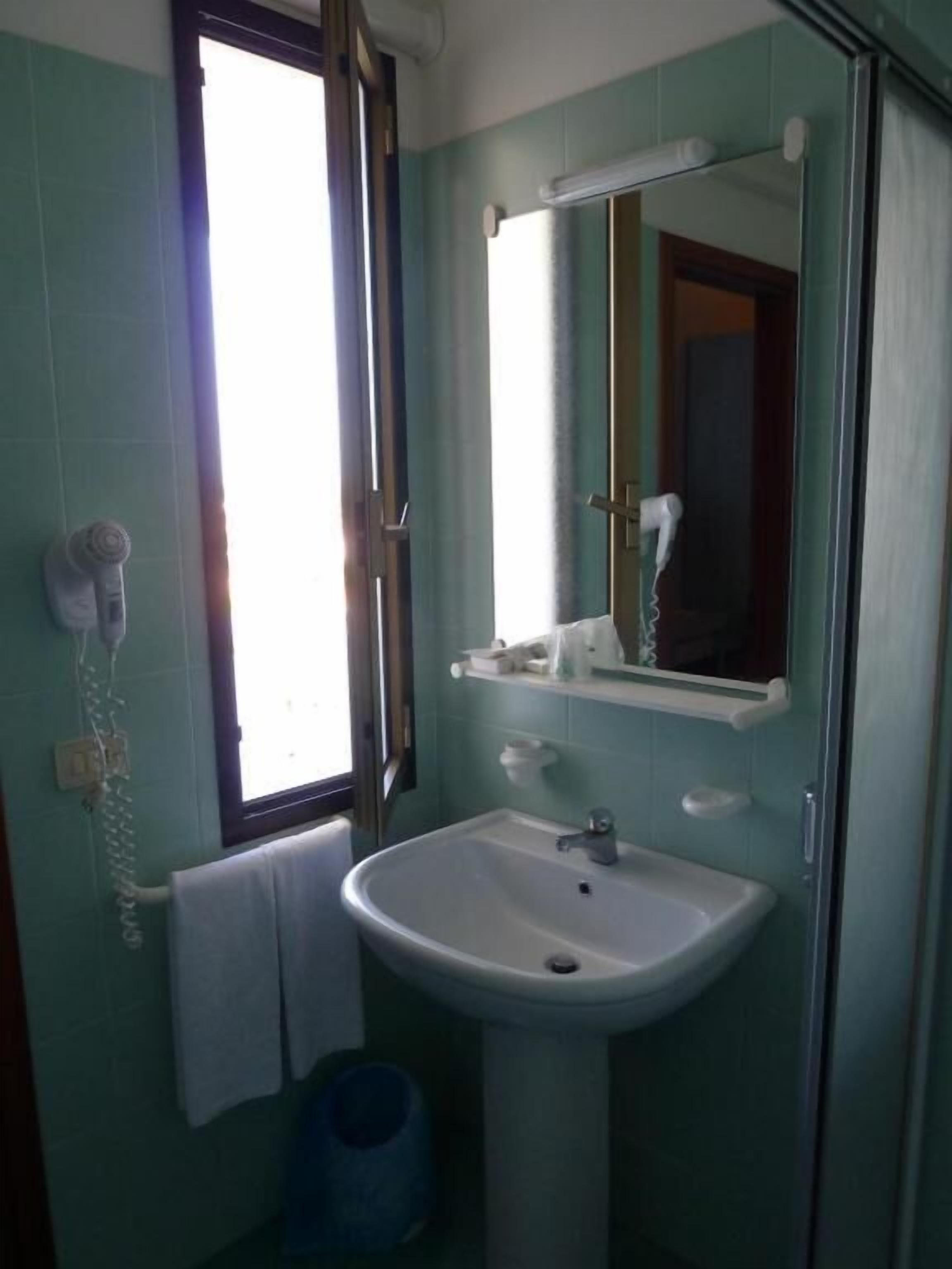 Ein Badezimmer mit Waschbecken, Spiegel und Fenster.