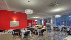 Een restaurant met marmeren vloeren, rode wanden en verschillende eetgedeeltes met tafels en stoelen.