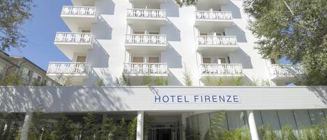 Et moderne hotel med hvid facade, flere balkoner og en tydelig indgang.