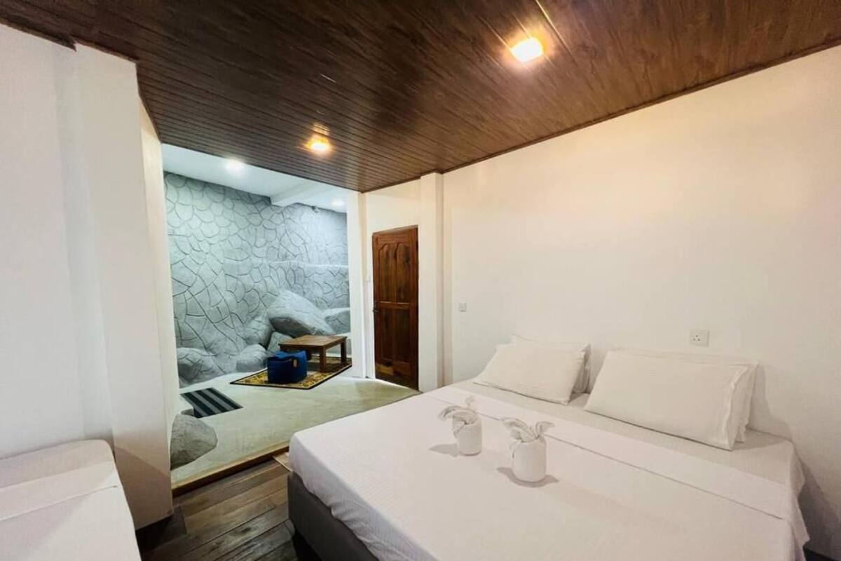 Un dormitorio con cama, techo de madera y pared de piedra.