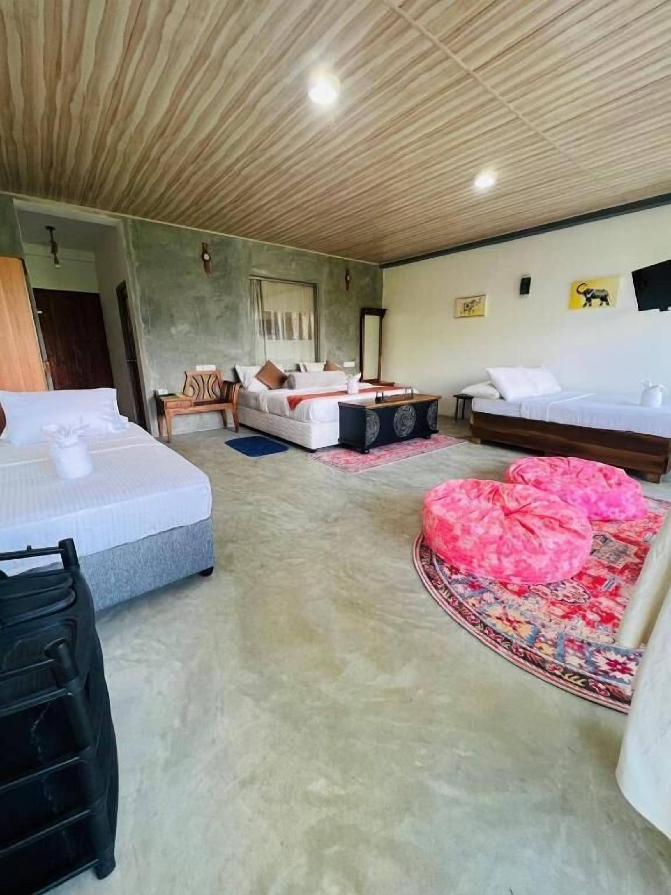 A room with two beds, a sofa, a small table, and a television on the wall.