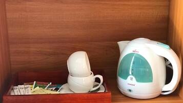 A wooden shelf with a white electric kettle and a tray containing a white mug and some books.