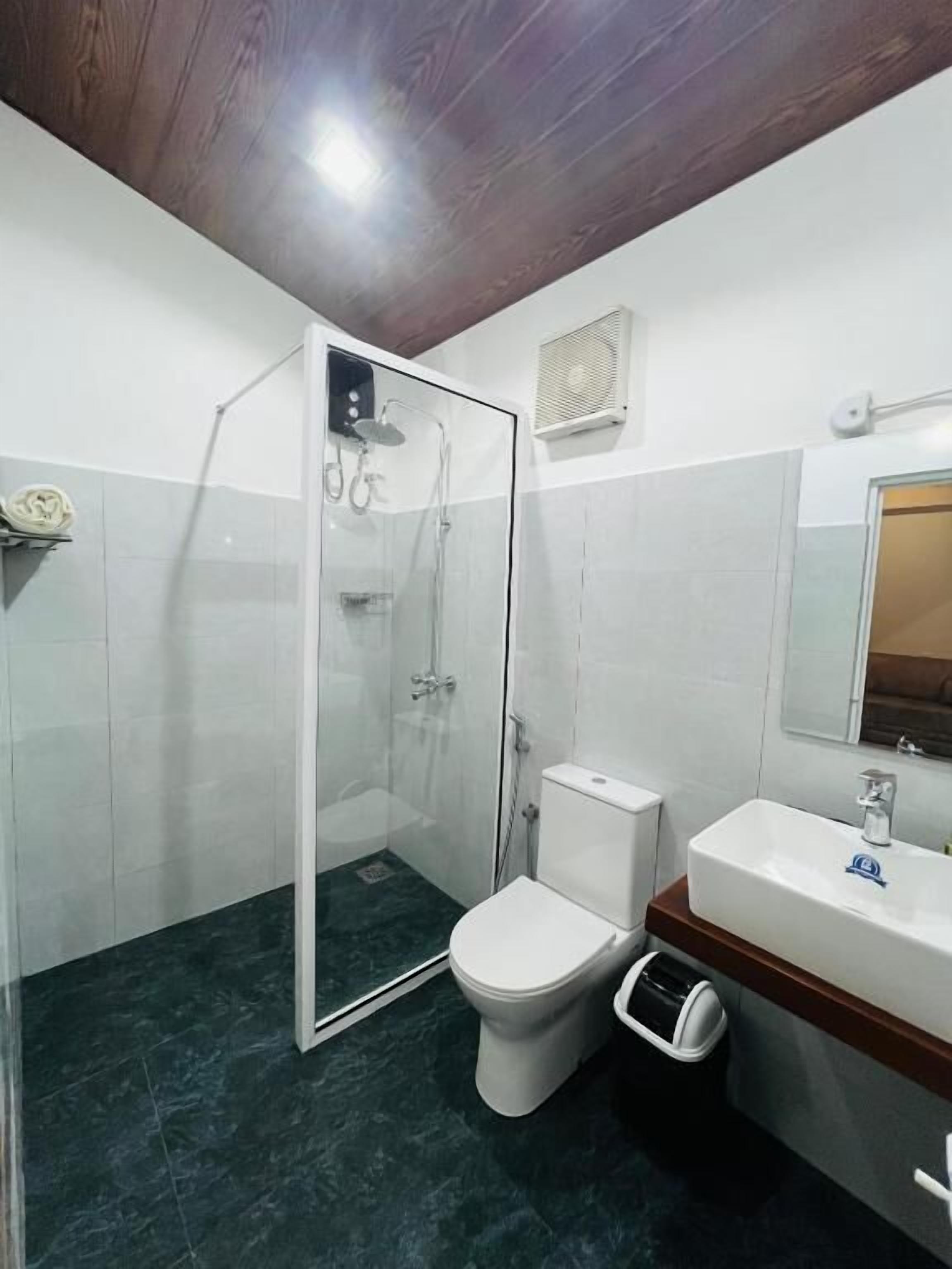A bathroom with a glass-enclosed shower, a toilet, and a sink.