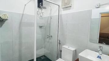 A bathroom with a glass-enclosed shower, a toilet, and a sink.