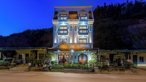 A large, multi-story building with a symmetrical facade, multiple balconies, and a well-lit entrance. - Lee Homestay SaPa (Sa Pa)