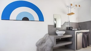 Un bagno moderno con uno specchio grande, un lavandino bianco e un elemento decorativo in pietra.