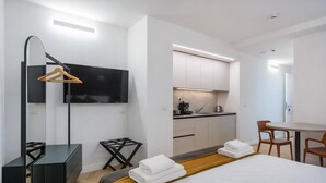 Une chambre d’hôtel moderne équipée d’un lit, d’un bureau, d’une télévision, d’un coin cuisine et d’une table à manger.