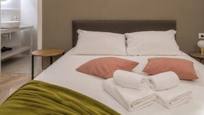 A hotel room with a bed, pillows, a bedside table, a lamp, and a mirror. - Hotiday Trieste Teatro (Trieste)