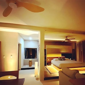 A modern hotel room with a bed, a ceiling fan, and a seating area. - PENTHOUSE PRINCE, loft & rooftop jaccuzi spa (Puerto Morelos)