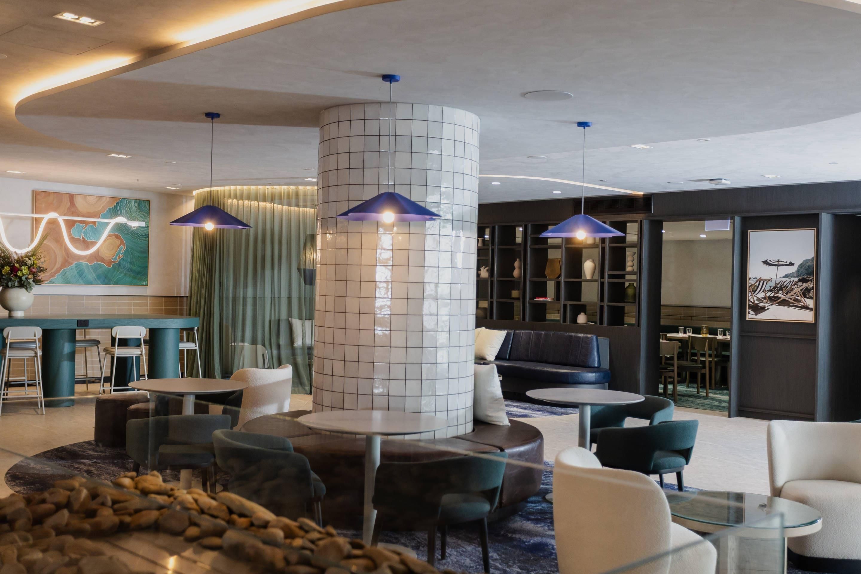 A modern lobby with a central column, seating areas, and pendant lighting.
