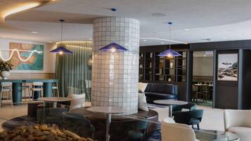 A modern lobby with a central column, seating areas, and pendant lighting.