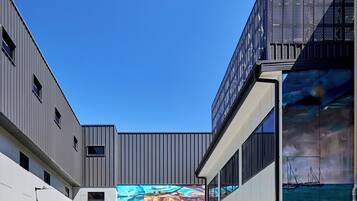 A modern building with a large mural, a staircase, and a clear blue sky.