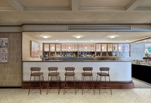 A bar area with a counter, stools, and a view of the cityscape through the window.