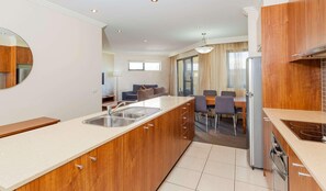A modern kitchen with wooden cabinets, a built-in sink, and a dining area with a table and chairs.