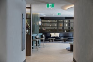 A modern lobby with a seating area, a reception desk, and a wall displaying various decorative items.