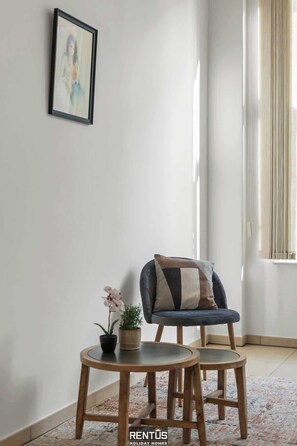 Ein Eckzimmer mit Stuhl, Tisch und einer Topfpflanze.
